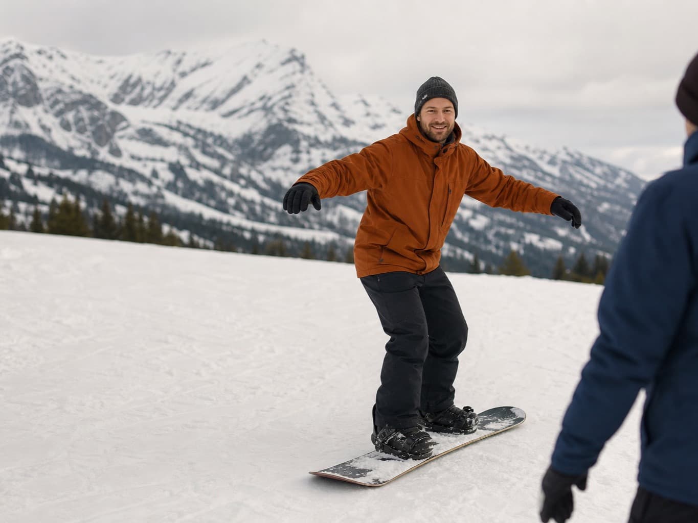 A rider standing on their board on a wide run, the snowy massif behind them